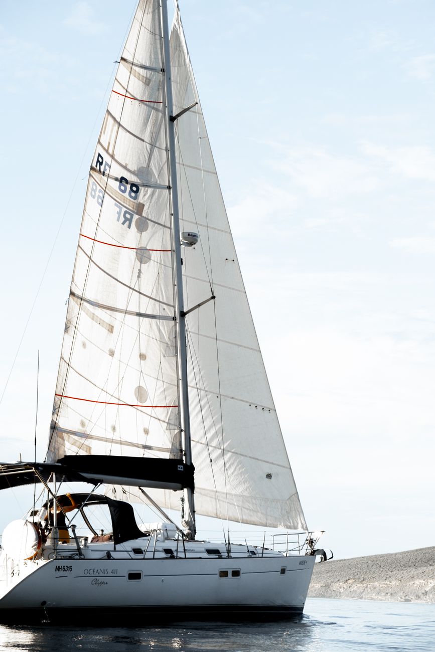 Sailboat gliding on tranquil water beneath a clear sky, capturing a serene nautical scene.