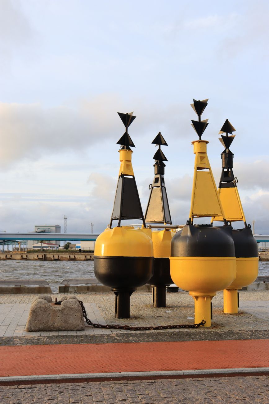 Yellow and black navigation buoys near the sea, offering a vibrant contrast against the sky.