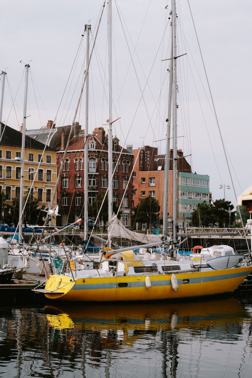 A vibrant marina scene showcasing sailboats and historic urban architecture on a calm water body.